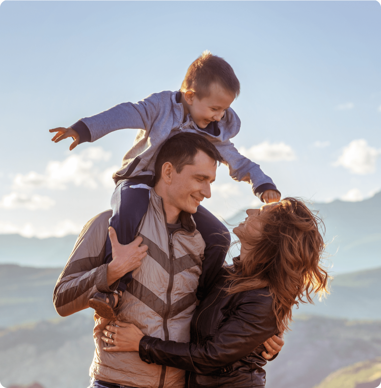 Father holding child on shoulders while mom looks at both of them